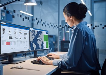 Factory Office: Portrait of Beautiful and Confident Female Industrial Engineer Working on Computer, on Screen Industrial Electronics Design Software. High Tech Facility with CNC Machinery